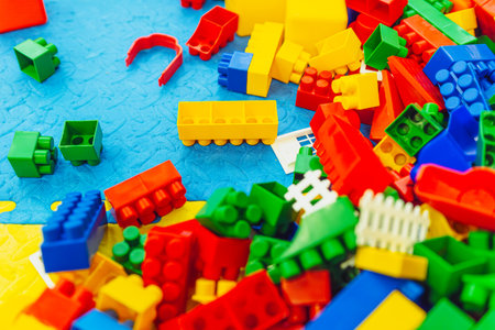 A vibrant assortment of plastic building blocks is spread across a colorful play mat in a children's...