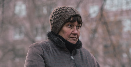 Thoughtful woman in knitted hat enjoys a quiet moment outdoors in early spring.