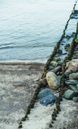 Stones and boulders line a sandy beach revealing a beautiful coastal landscape at low tide The calm...