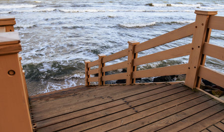 Serene View of Rocky Shoreline From Wooden Steps on a Cloudy Day.の写真素材