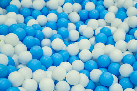 Colorful blue and white balls scattered on a play area floor, perfect for children's activities and fun playtime moments.の写真素材