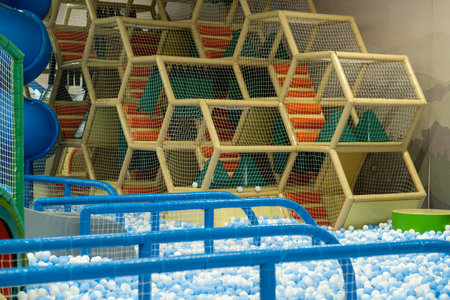 Brightly colored climbing structures with mesh walls create an engaging play area filled with white...