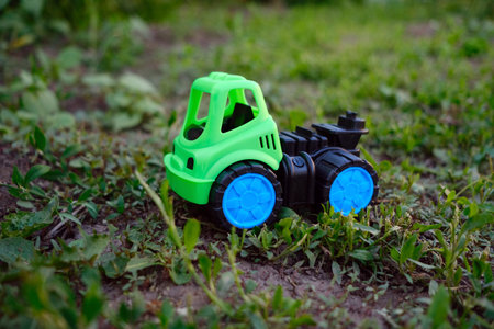 A bright green toy truck rests on the lush grass showcasing its vibrant colors Sunlight illuminates the scene creating a playful atmosphere perfect for outdoor adventures.の写真素材