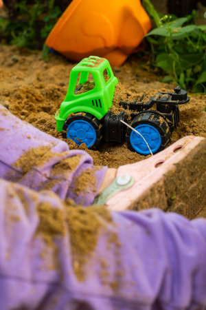 A child plays with a toy truck on the sand on a sunny day outdoors.の写真素材
