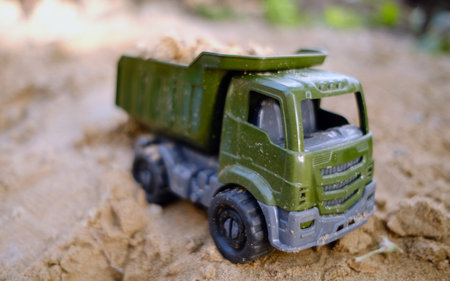 A toy dump truck rests on the sandy surface filled with sand showcasing vibrant colors against the natural earth Perfect for imaginative play outdoors inviting creativity.の写真素材