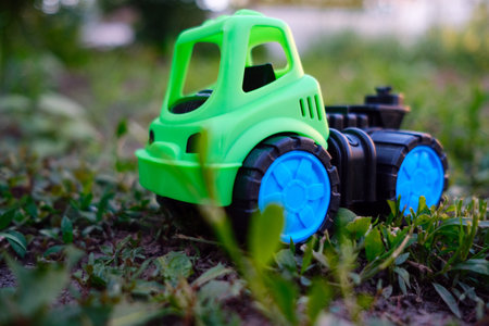 A bright green toy truck rests on the lush grass showcasing its vibrant colors Sunlight illuminates the scene creating a playful atmosphere perfect for outdoor adventures.の写真素材