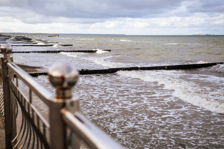 Waves Gently Lap Against Wooden Groynes Along the Shore Under a Cloudy Sky in a Coastal Area.の写真素材