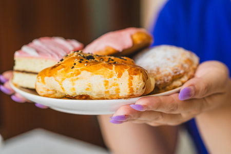 A variety of sweet pastries including layered cake and flaky croissants are presented on a plate A person holds the plate enjoying a moment of indulgence during an afternoon meet-upの写真素材
