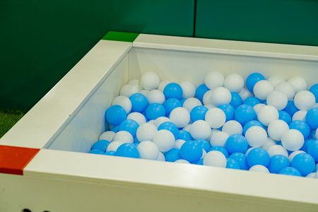 Bright blue and white balls fill a large square pit designed for kids to jump in and have fun. This...