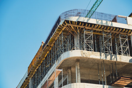 Construction site showing progress on a multi-story building under a clear blue sky.
