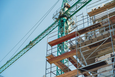 Construction site with crane and scaffolding under clear blue sky in urban area.