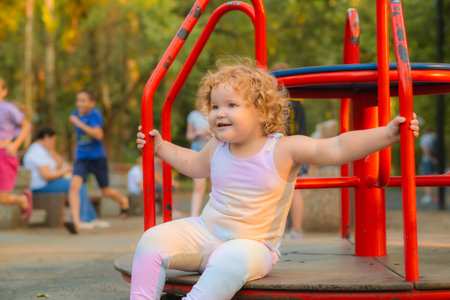 A joyful child swings on a red swing set in a park filled with greenery, enjoying a sunny afternoon with laughter and playful energy surrounding the areaの写真素材