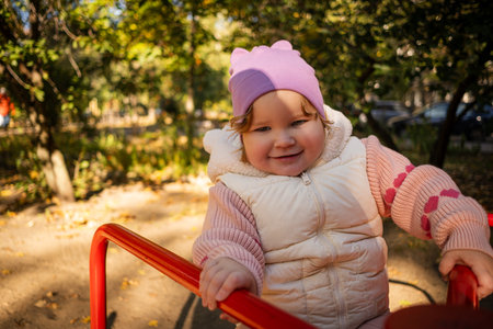 A cheerful child rides on a vibrant carousel in a lively park surrounded by colorful autumn leaves. The sun shines brightly as joyful laughter fills the air.の写真素材