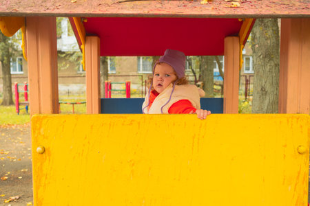 Little girl explores bright playground structure during a cool autumn day in a lively neighborhood parkの写真素材