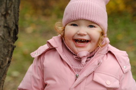 Portrait of a cute little girl in a pink coat and hatの写真素材