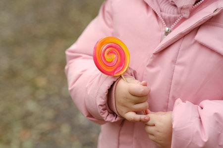 Little girl holding colorful lollipop in park, closeup viewの写真素材