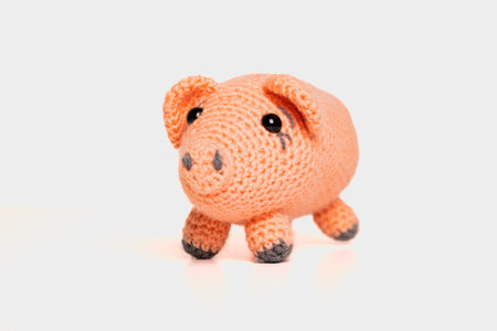 Cute crochet pig toy sitting on a plain background, perfect for kids and collectors alikeの写真素材