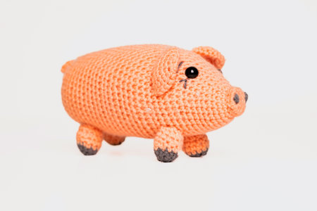 A small, hand-crocheted pig toy features a soft orange body and charming details. Ideal for children or as a decorative item in any playful setting.の写真素材