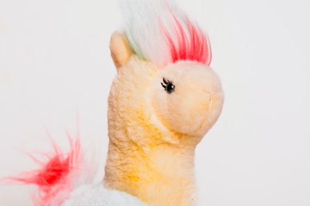 This cheerful toy lama features a colorful mane with pink, blue, and white tones. Its friendly expression adds charm, making it perfect for play or display.の写真素材