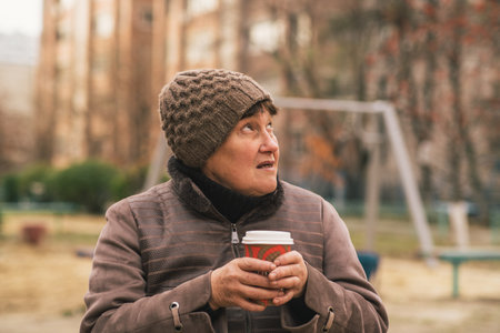 Thoughtful woman in knitted hat enjoys a quiet moment outdoors in early spring.の写真素材