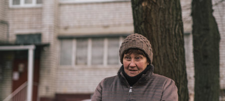 Elderly woman reflecting thoughtfully in urban park during a cool afternoon in early autumn.の写真素材