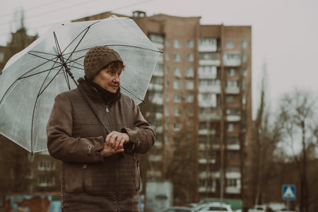 Thoughtful woman holding a transparent umbrella on a rainy day in an urban environment while contemplating life.の写真素材