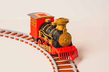 A toy train moves along a curved track, combining classic design with vibrant colors. This playful model captures the charm of vintage locomotives, perfect for children and collectors alikeの写真素材
