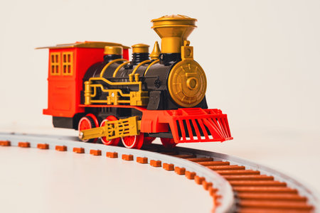 A toy train moves along a curved track, combining classic design with vibrant colors. This playful model captures the charm of vintage locomotives, perfect for children and collectors alikeの写真素材