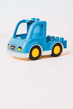 A vibrant blue toy truck sits on a bright white surface. The truck features yellow wheels and a blocky design, inviting creative playtime for children.の写真素材