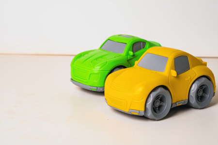 Two vibrant toy cars, one green and one yellow, sit side by side. They have smooth wheels and are ideal for imaginative play, inviting kids to create exciting racing storiesの写真素材