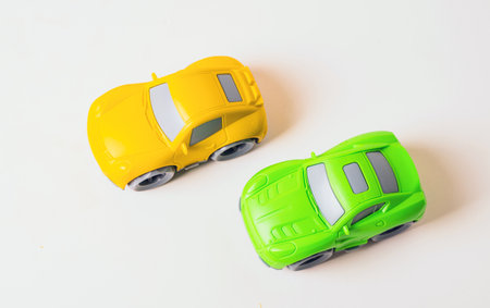 Two vibrant toy cars, one green and one yellow, sit side by side. They have smooth wheels and are ideal for imaginative play, inviting kids to create exciting racing storiesの写真素材