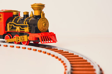 A toy train moves along a curved track, combining classic design with vibrant colors. This playful model captures the charm of vintage locomotives, perfect for children and collectors alikeの写真素材