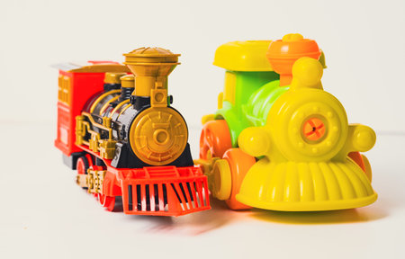 Two vibrant toy trains sit on a white surface, inviting children to engage in creative play. One is classic steam engine style while the other features a cheerful design.の写真素材