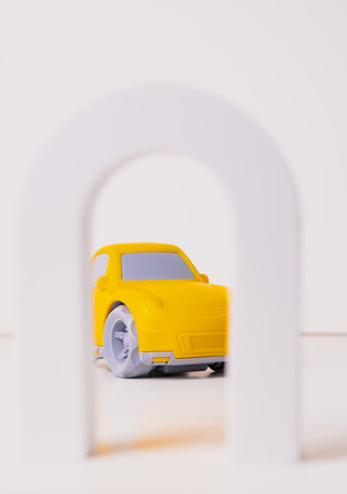 Bright yellow toy car seen through a white arch in a playful and imaginative settingの写真素材