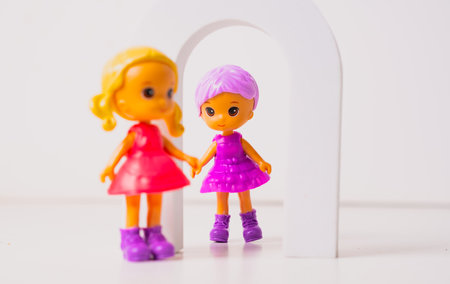 Colorful toy dolls playing together in a vibrant setting with feathers and an arch.の写真素材