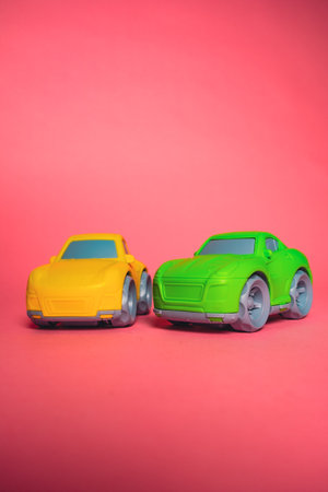 Two toy cars on a pink background during a play session with friends in a simple settingの写真素材