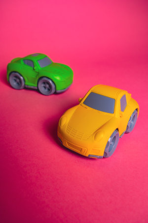 Two toy cars on a pink background during a play session with friends in a simple setting