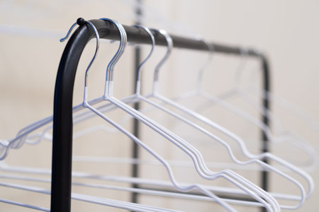 A row of white plastic hangers neatly hung on a black clothing rack, empty and ready for use.の写真素材