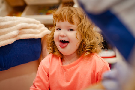 Young child with red curly hair sticking out her tongue playfully for a funny portrait. Childhood...
