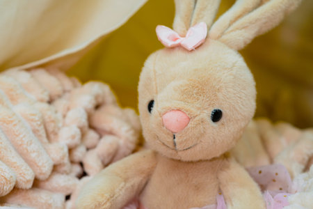 Plush bunny toy with pink bow and tutu on soft blanket. Cute animal doll for baby and child, gift for Easter or birthdayの写真素材