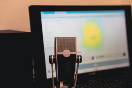 Microphone on desk with laptop in background. Online podcast, radio host, voice recording setup....