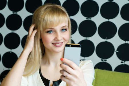 Blonde girl sitting in cafe holds a smartphone
