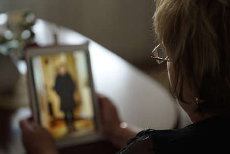 Adult woman sitting at the table holds digital computer tablet and looking her photos on display of computer tablets. Close-upの写真素材
