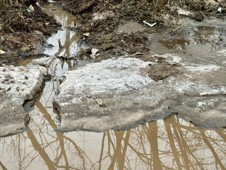 Melting dirty snow on the streets of the city during the daytime in winter. A big puddle on the...
