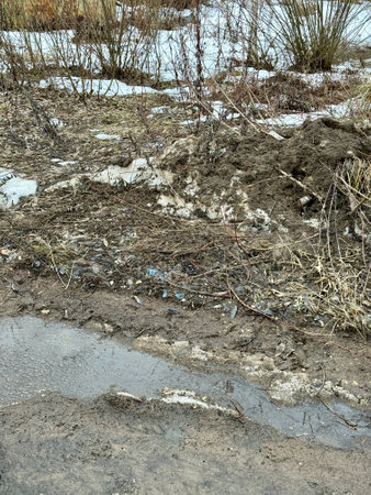 Melting dirty snow on the streets of the city during the daytime in winter. Snow with sand and mud lies on the roadの写真素材