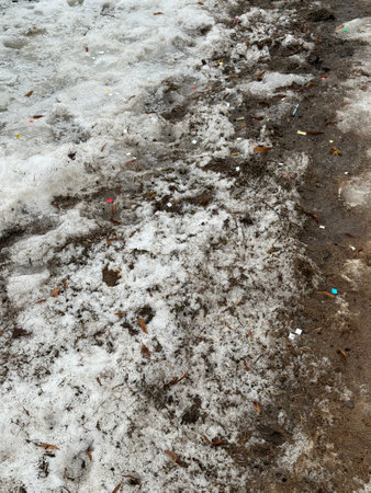 Melting dirty snow on the streets of the city during the daytime in winter. Snow with sand and mud lies on the roadの写真素材