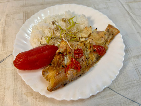 Sea bass on a white plate with bean sprouts, rice and tomato. Healthy eating at home.の写真素材