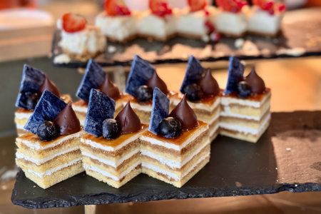The portions of layered cream cake with blueberry on a black stand on the counter of the restaurant. Close-upの写真素材