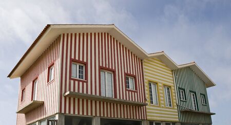 Three typical houses from the beach of Vieira de Leiria, one with red stripes, one with yellow stripes and one with green stripes.の写真素材