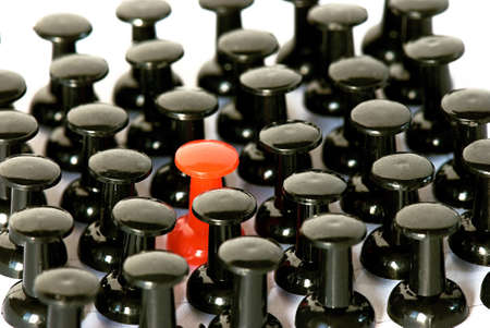 Even array of black pushpin and one red pushpin close-upの写真素材